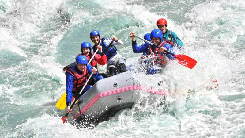 Rafting Garmisch Eine Gruppe von Menschen in einem Schlauchboot auf dem Wasser, alle tragen Schwimmwesten.