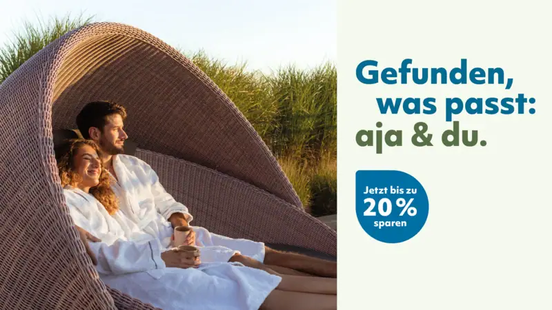 aja & du Ein Paar im Bademantel liegt in einem Korbsessel