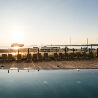 Außenpool Ein Pool mit Stühlen und einem Boot im Hintergrund.