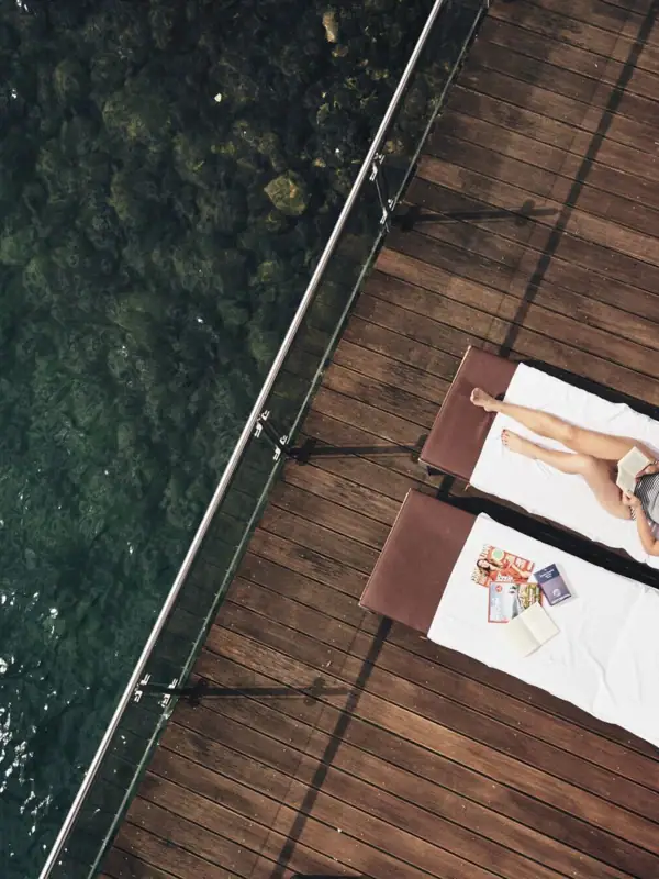 Liege am See Eine Frau liegt auf einem Liegestuhl neben Wasser.