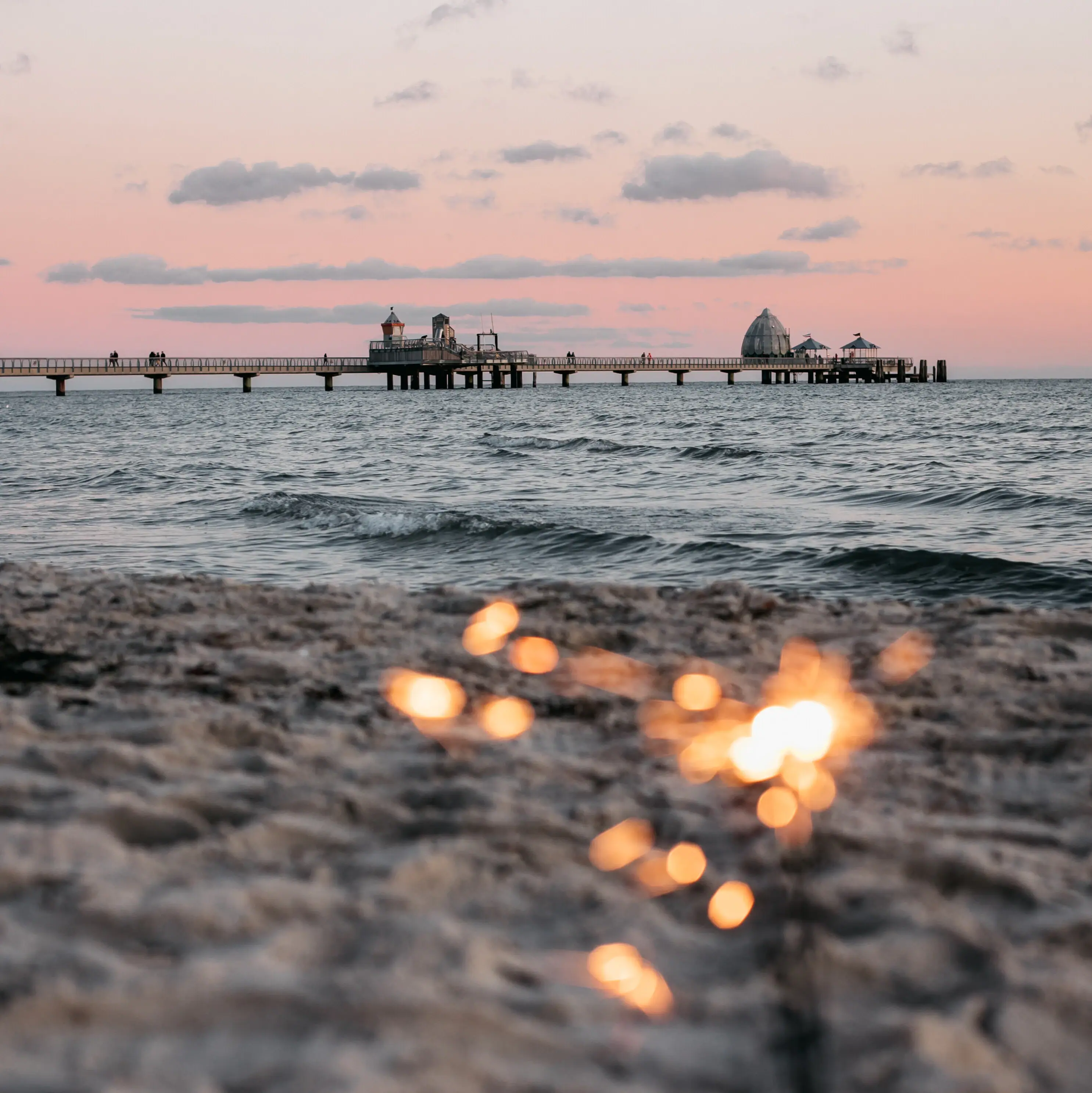 Silvester Grömitz Ein Strand mit einem Pier im Hintergrund.
