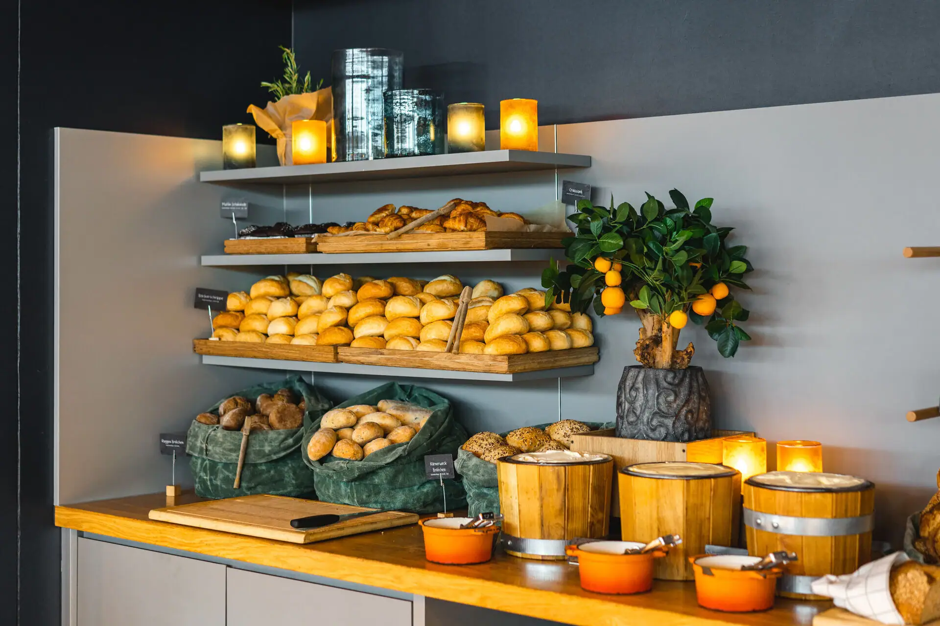 Brötchen am Buffet Ein Regal mit Brot und verschiedenen Brötchen sowie drei kleine Butterfässer.