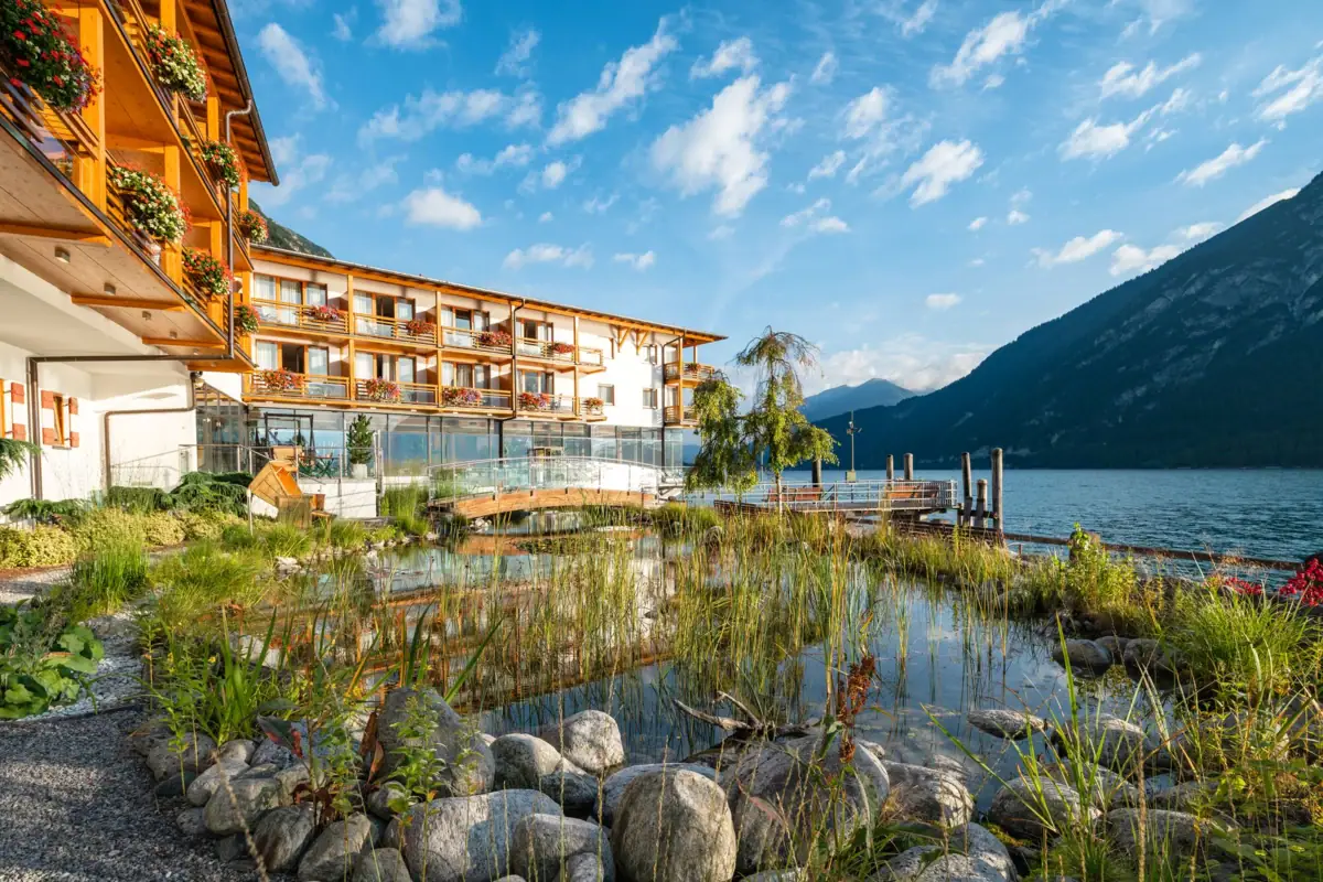 Fürstenhaus am Achensee Ein Gebäude mit einem Gewässer und Bergen im Hintergrund.