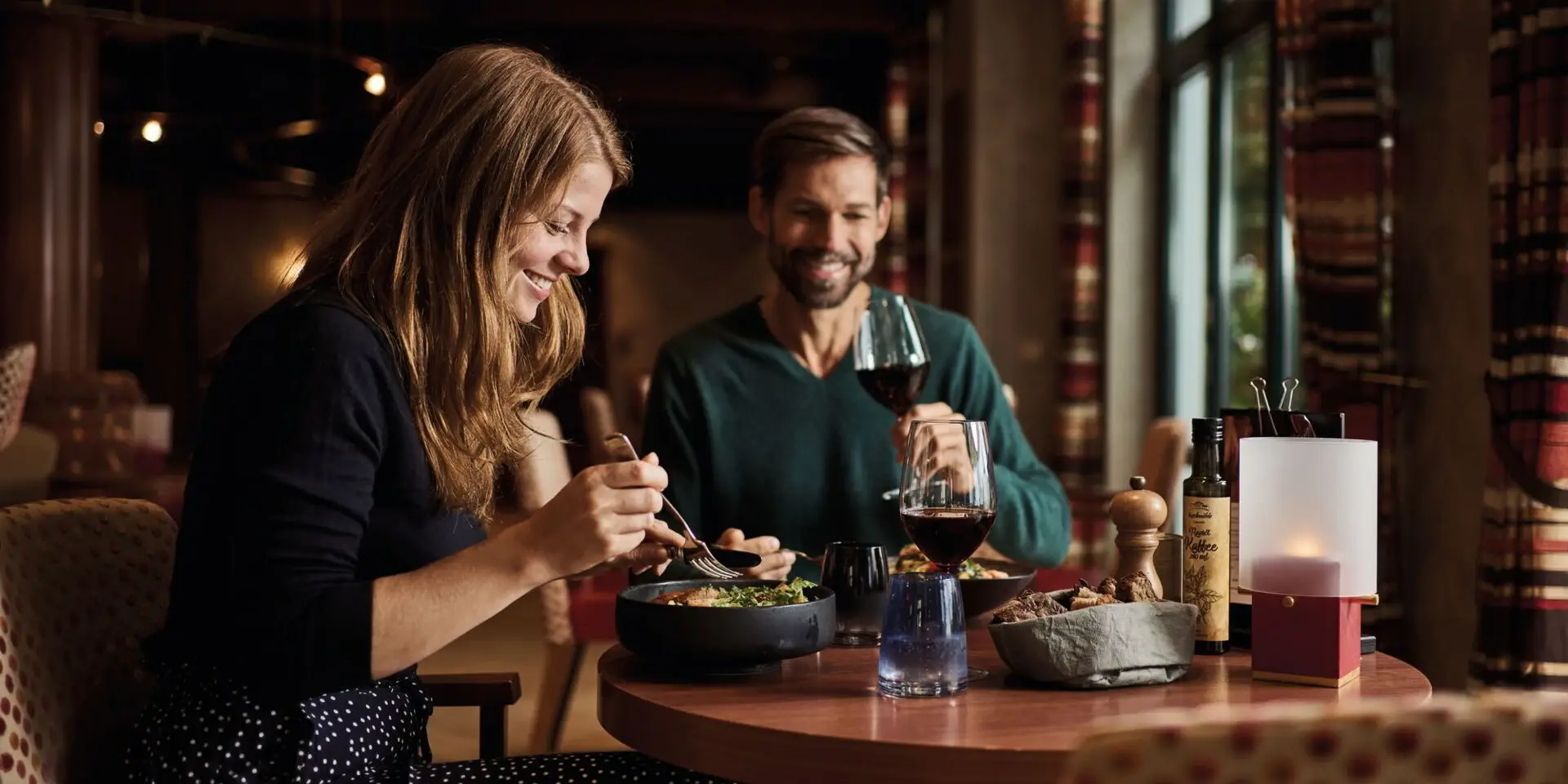 Bistro aja Bansin Ein Mann und eine Frau sitzen beim Essen an einem Tisch im Restaurant, mit Weingläsern und einer Flasche Wein.