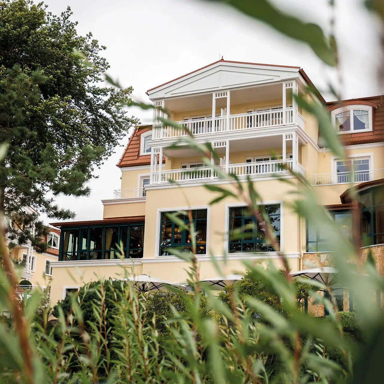 aja Strandhotel Bansin Ein Gebäude mit Fenstern und Bäumen im Hintergrund.
