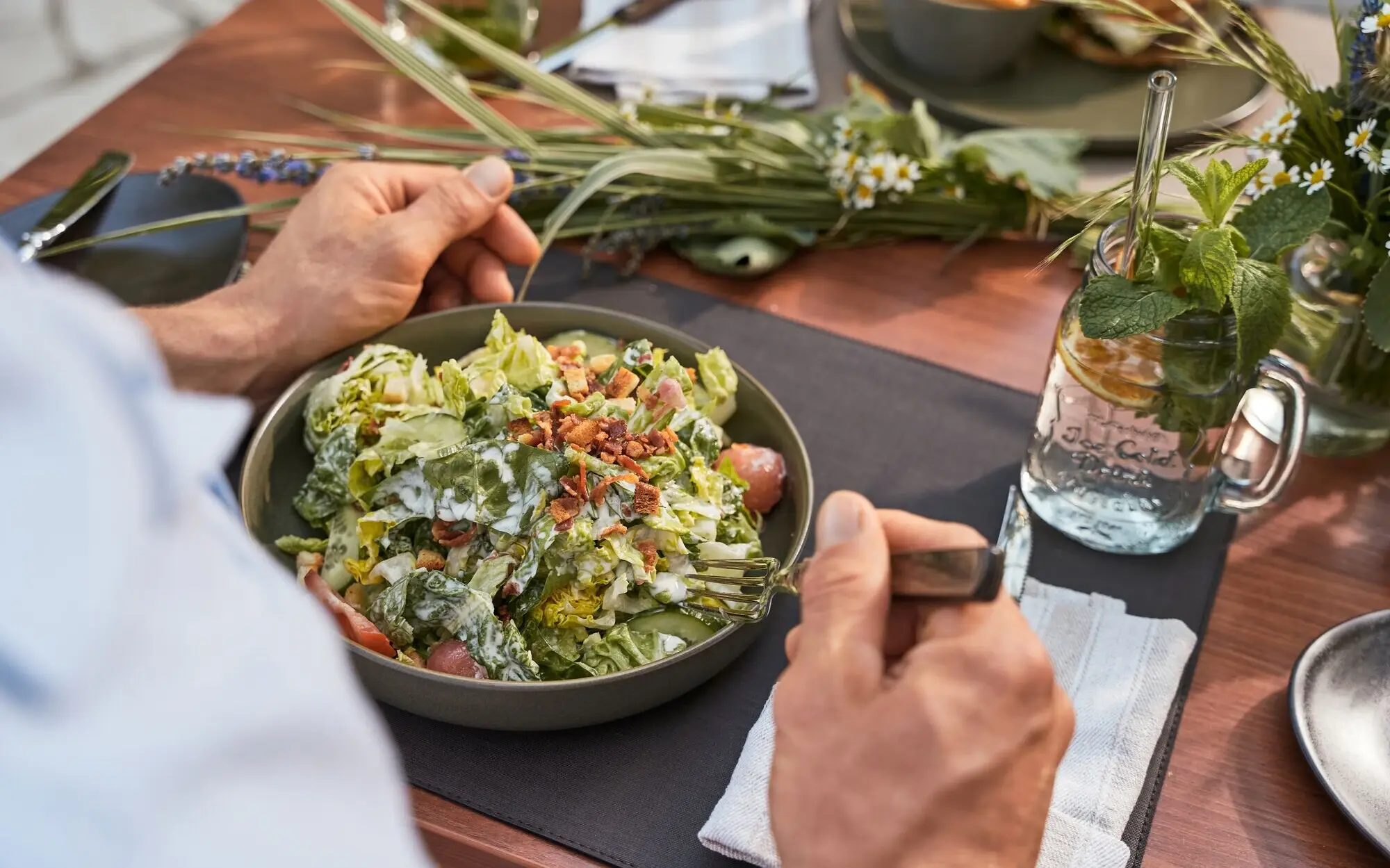 vegetarisches Gericht Ein Mensch isst einen Salat an einem gedeckten Tisch.