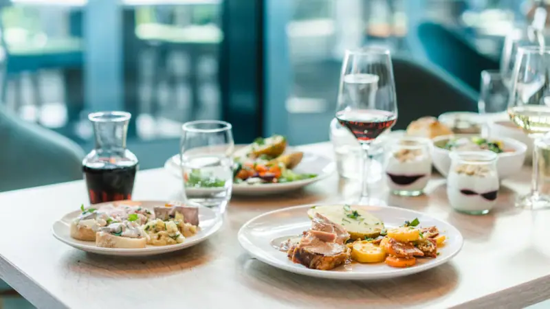Abendessen Ein Tisch mit Tellern voller Speisen und Gläsern Wein.