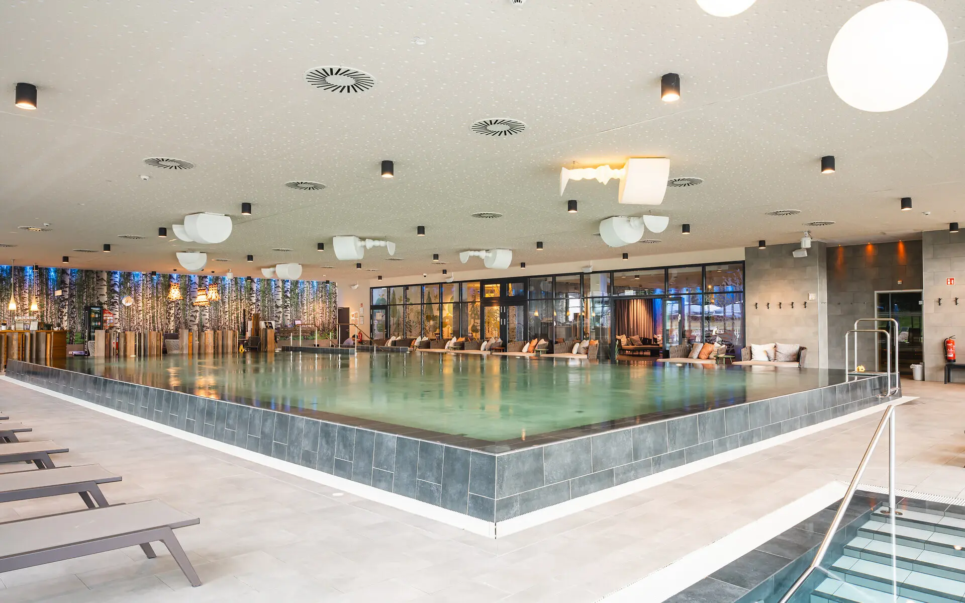 Innenpool aja Bad Saarow Der Innenpool des aja Bad Saarow von der Ecke fotografiert mit vielen Liegen und angenehmen Lichtern zum wohlfühlen.