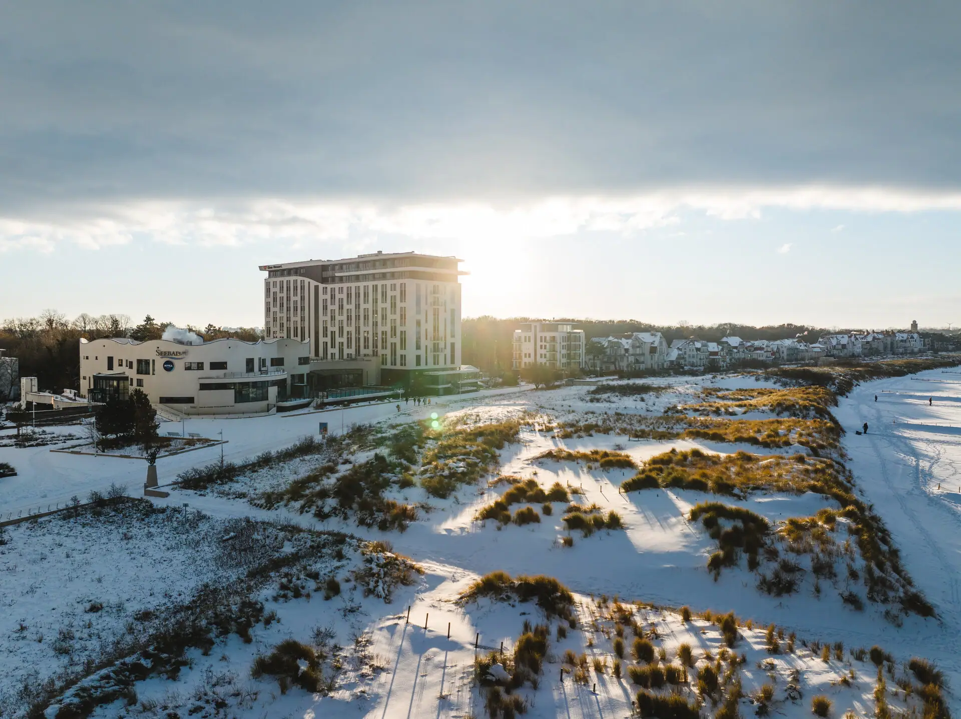 aja Warnemünde Ein schneebedecktes Feld mit dem aja Warnemünde im Hintergrund.