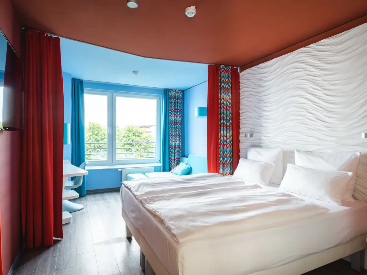 Doppelzimmer Ein Zimmer mit zwei Betten und roten Vorhängen.