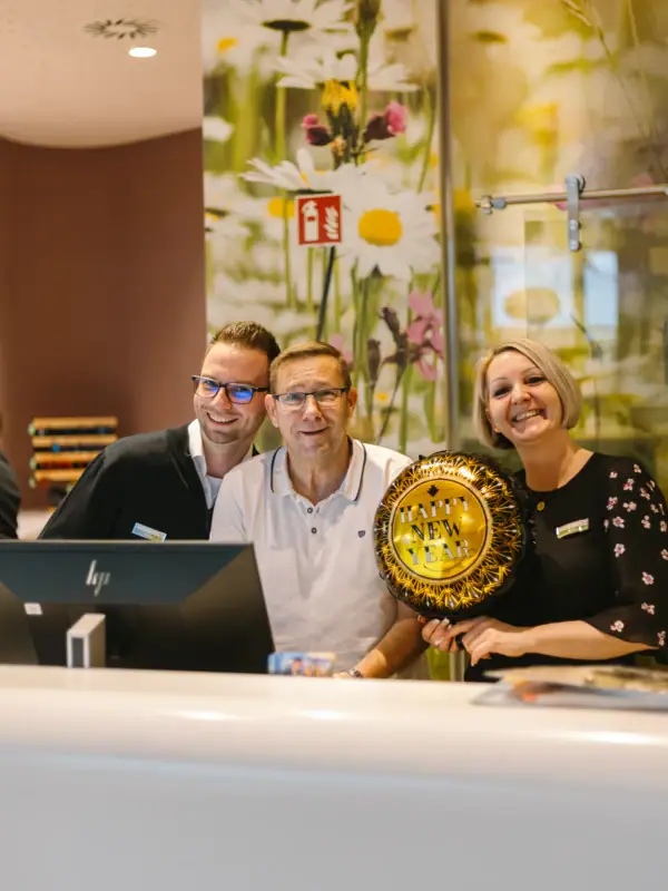 Silvesterparty im aja Bad Saarow Eine Gruppe von Menschen steht an der Rezeption und lächelt in die Kamera.