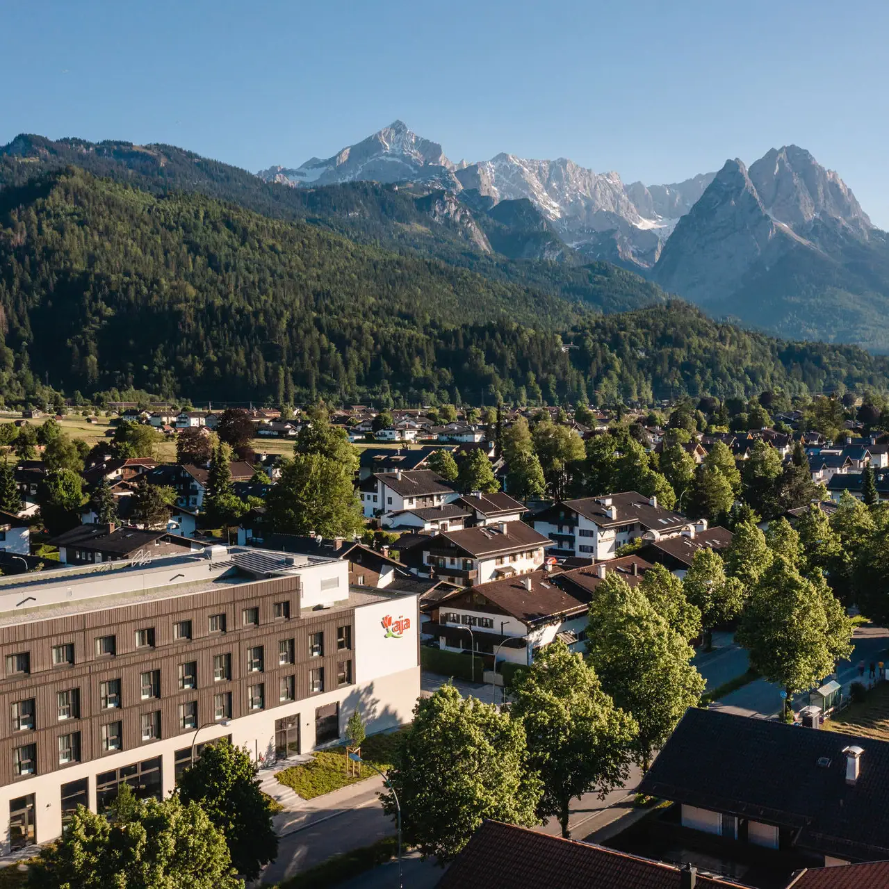 aja Garmisch-Partenkirchen Eine Stadt mit Bäumen und Bergen im Hintergrund.