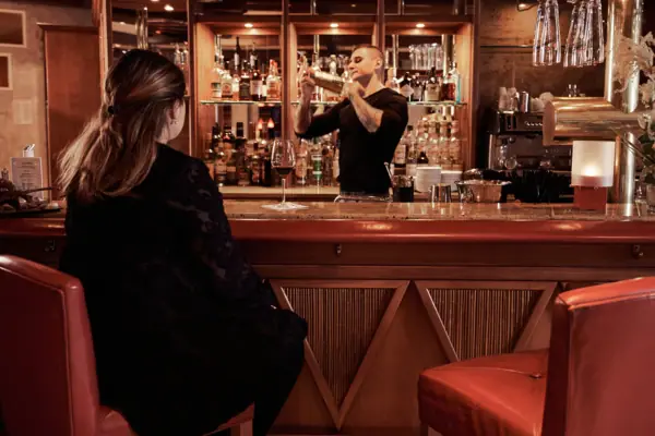 Bistro & Bar Patio Ein Mann und eine Frau in schwarzen Kleidern sitzen an einer Bar.