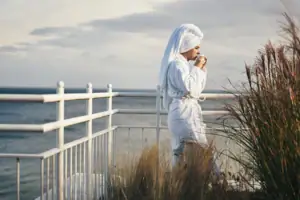 Eine Frau im Bademantel trinkt aus einer Tasse.