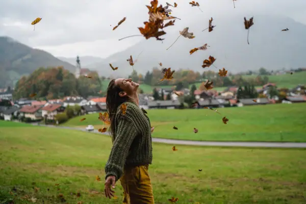 Herbst in Ruhpolding Eine Frau wirft Laub in die Luft.