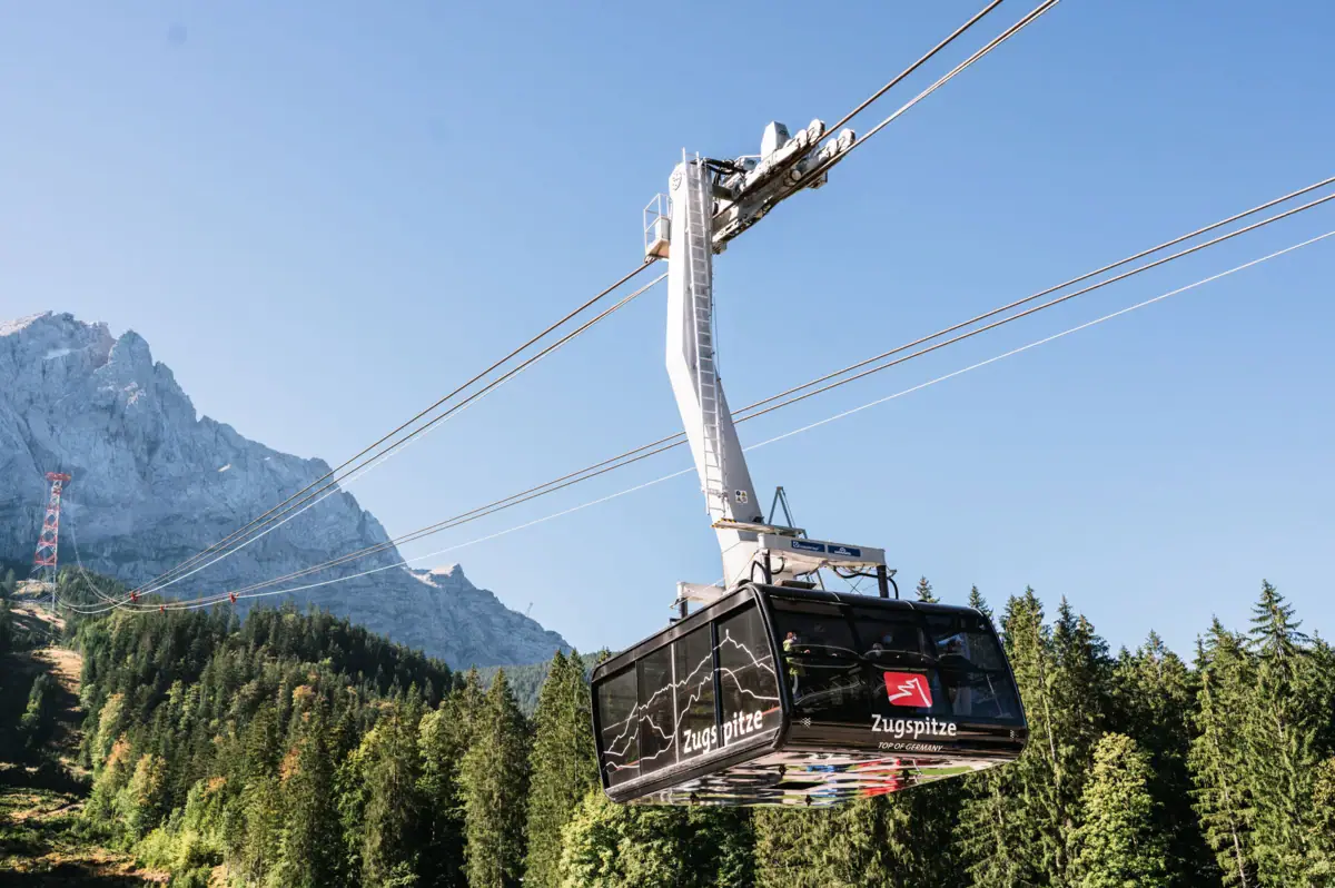 Zugspitz Seilbahn Die Zugspitz Seilbahn mit Bäumen und Bergen im Hintergrund.
