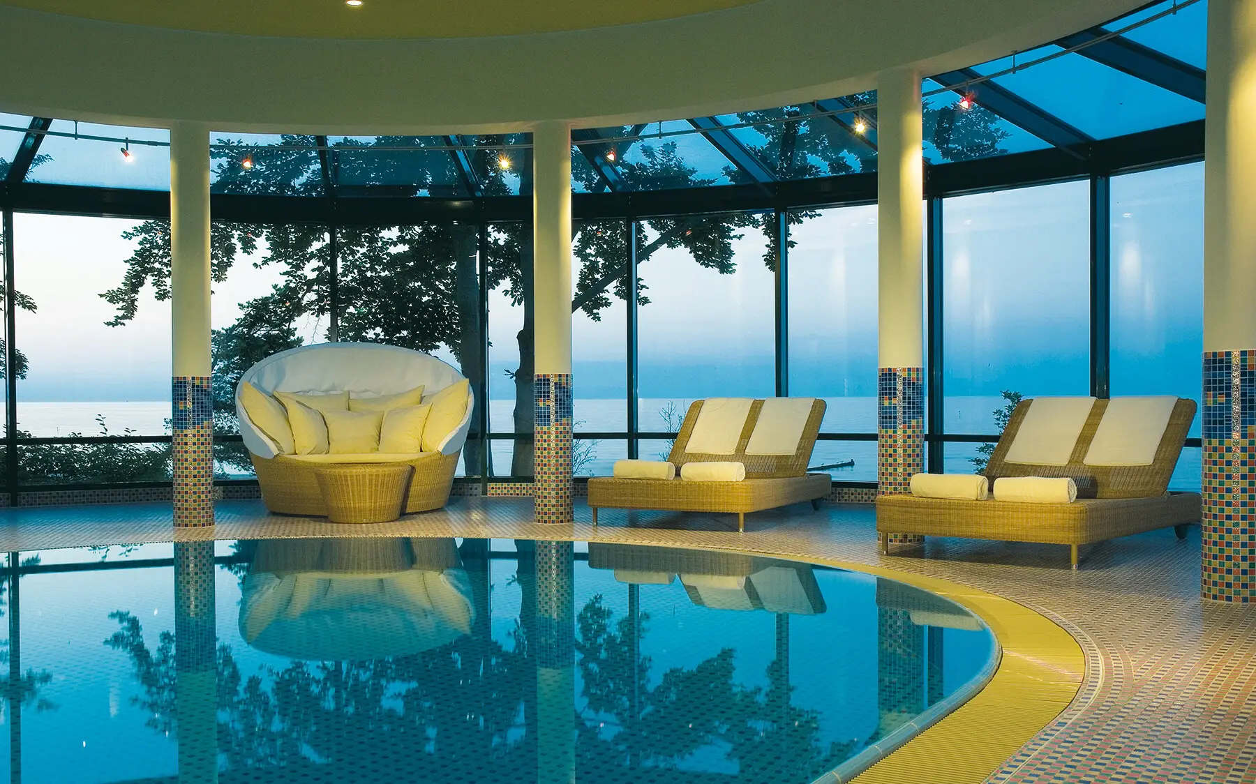 Innenpool aja Bansin Poolbereich mit Stühlen und einem großen Fenster in einem Resort.