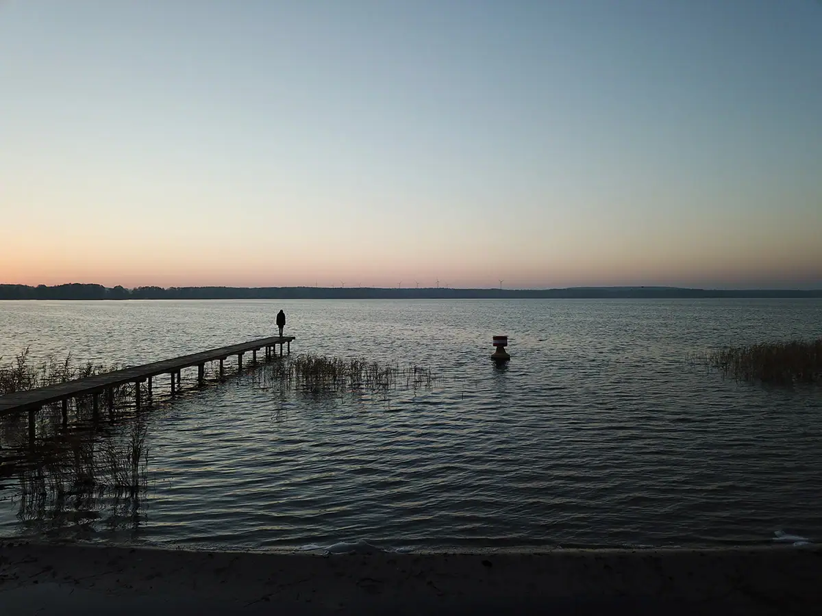 Scharmützelsee Eine Person steht auf einem Steg im Wasser.