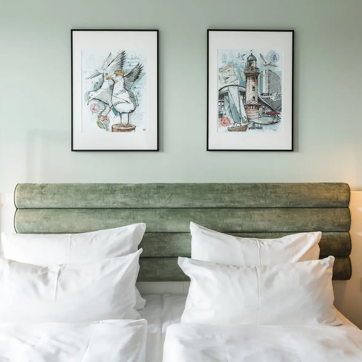 Zimmer und Suiten im aja Warnemünde Bett mit weißen Kissen und grünem Kopfteil, flankiert von zwei Lampen.