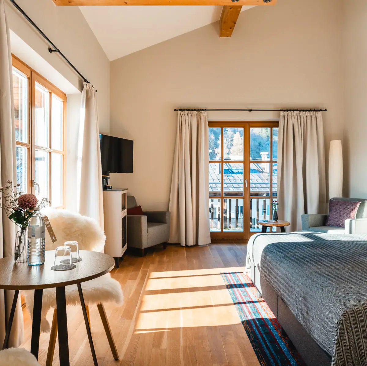 HENRI Kitzbühel Zimmer mit einem Bett und einem Tisch mit Stühlen.