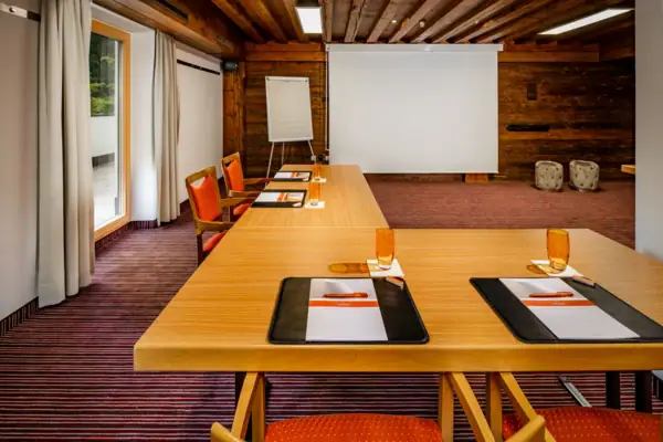 Meetingraum Ein Raum mit einer großen weißen Leinwand und mehreren Tischen.