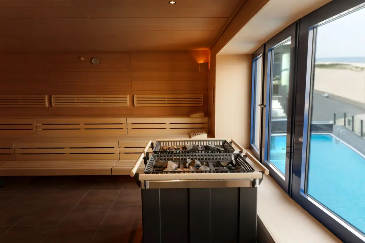 Sauna Eine Sauna mit einem Fenster durch das ein Pool zu sehen ist.