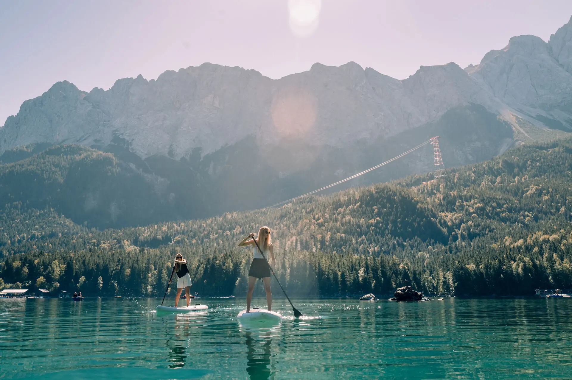 SUP Eibsee Zwei menschen fahren auf dem Eibsee mit einem stand up paddle board