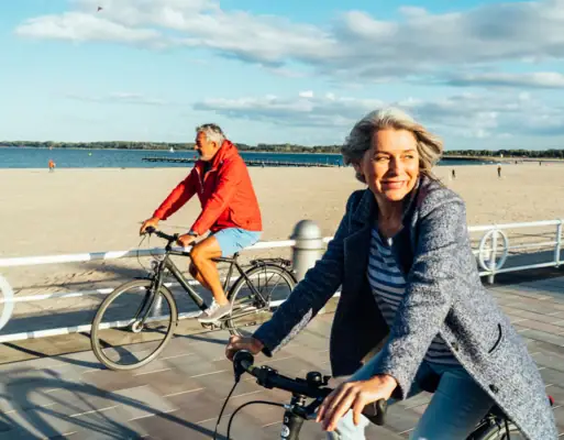 Radfahren Ein Mann und eine Frau fahren mit Fahrrädern am Strand entlang.