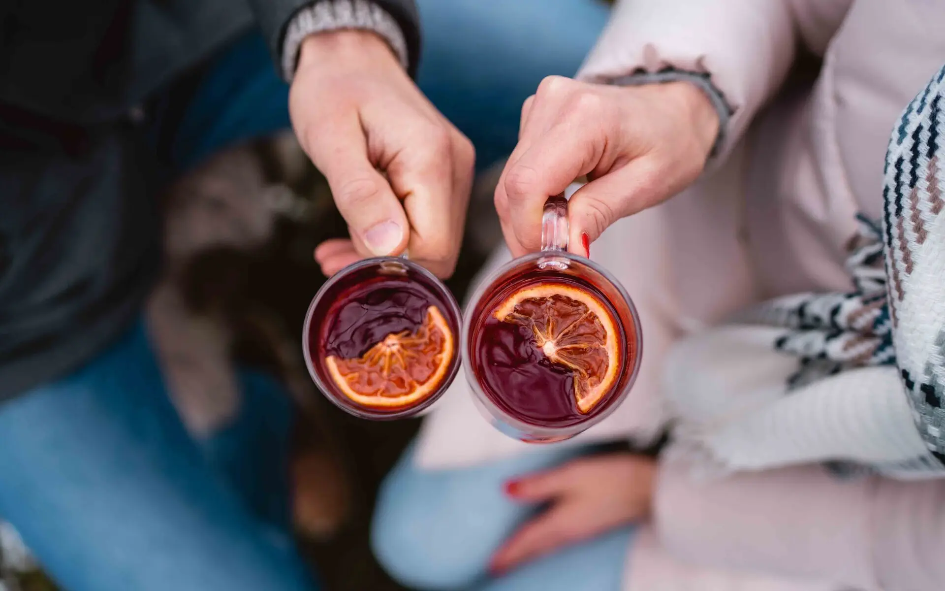 Drinks Zwei Personen halten Gläser mit Glühwein in ihren Händen.