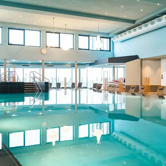 Badewelt Großes Hallenbad mit Stühlen und Treppe.