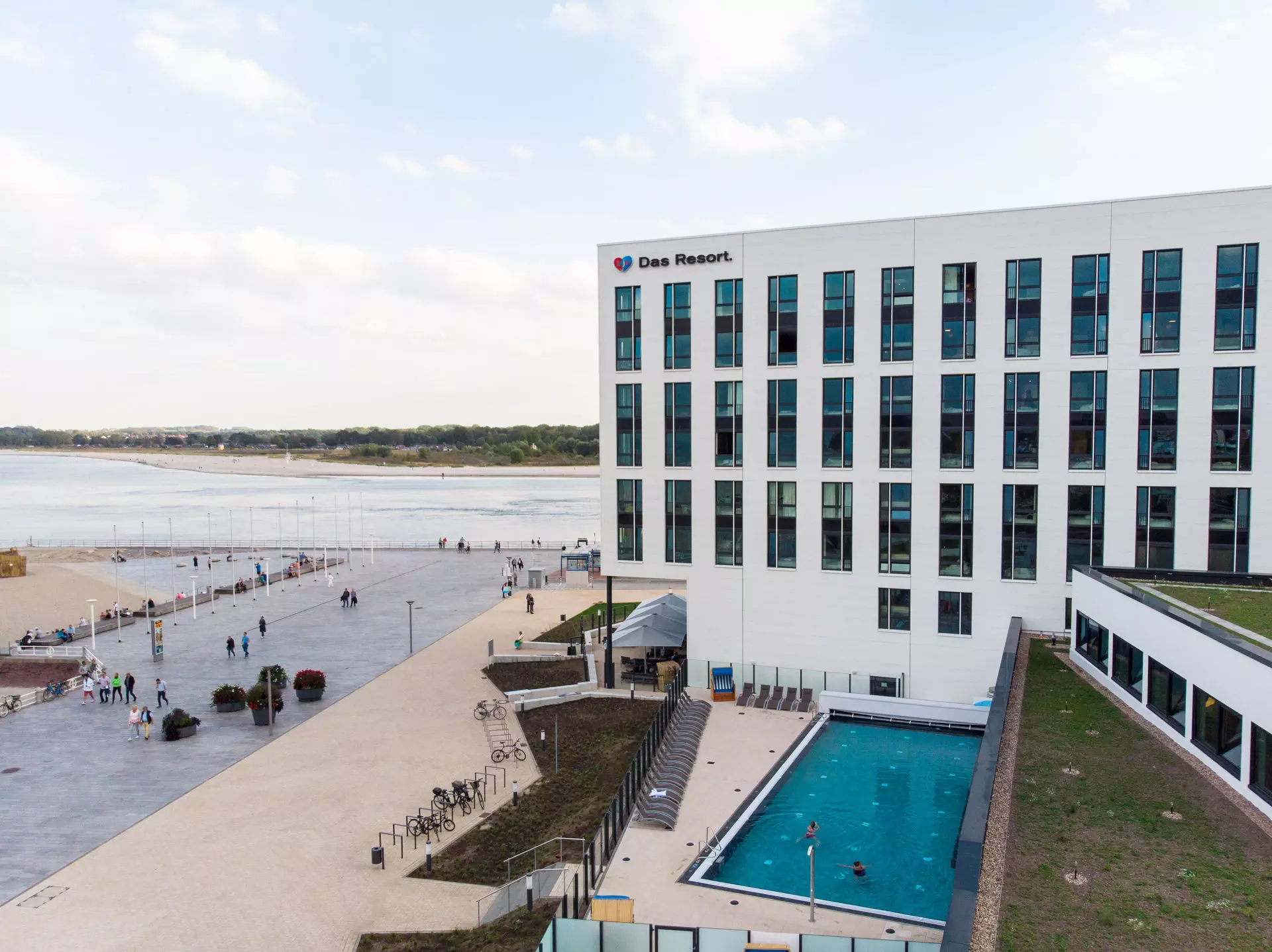 aja Travemünde Ein Gebäude mit einem Schwimmbad und Menschen, die herumlaufen.