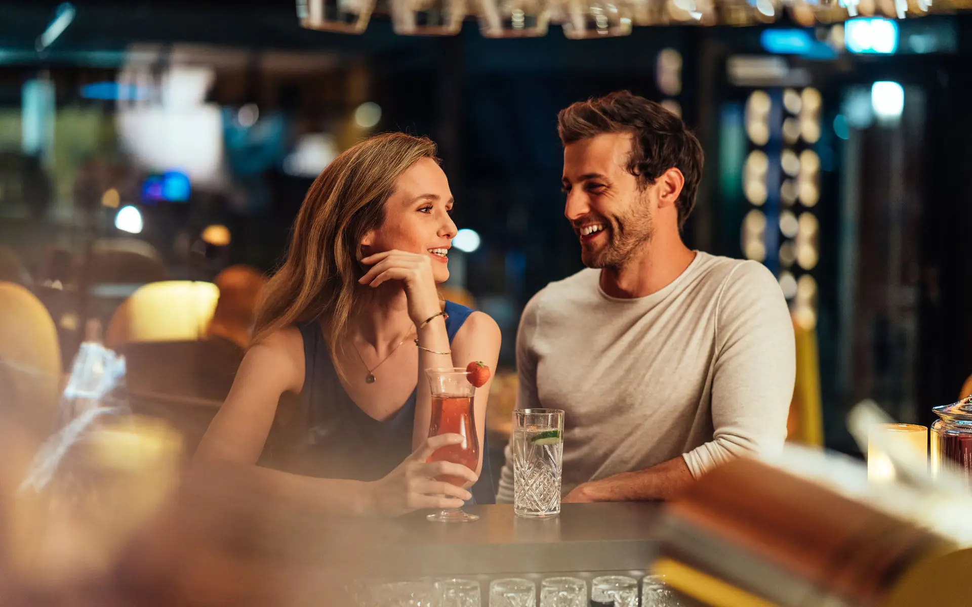 Ein Paar sitzt in einer Bar mit entspannter Atmosphäre und trinkt Cocktails.