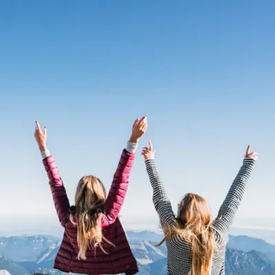 Zugspitze Aussicht Zwei Frauen stehen auf einem Berg mit erhobenen Armen.