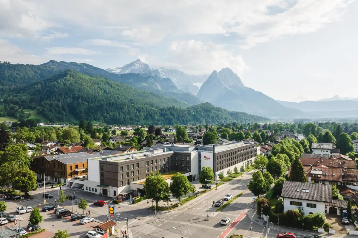 aja Garmisch-Partenkirchen Stadtansicht mit vielen Gebäuden und Bäumen unter einem bewölkten Himmel.