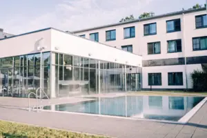 Außenpool Ein Gebäude mit einem Pool und Fenstern.