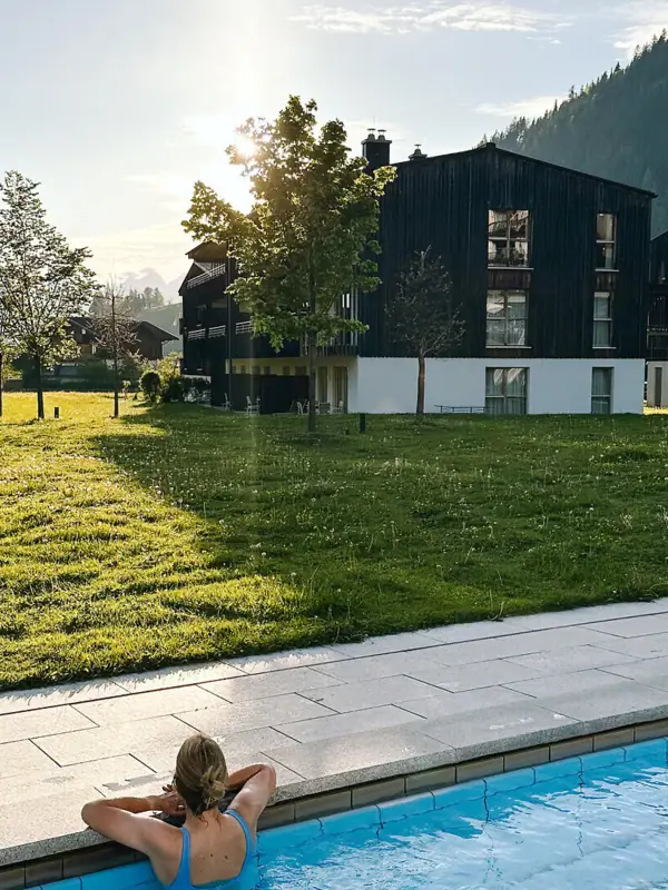 Badewelt im aja Bergresort Werfenweng Eine Frau in einem Pool mit Gras und Bäumen im Hintergrund.