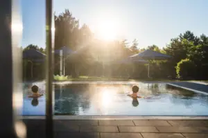 Außenpool Ein Mensch schwimmt in einem Außenpool bei Sonnenschein.