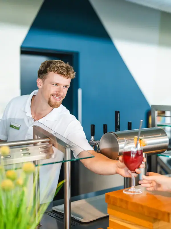 Ein Mann reicht einem Kunden ein Getränk.
