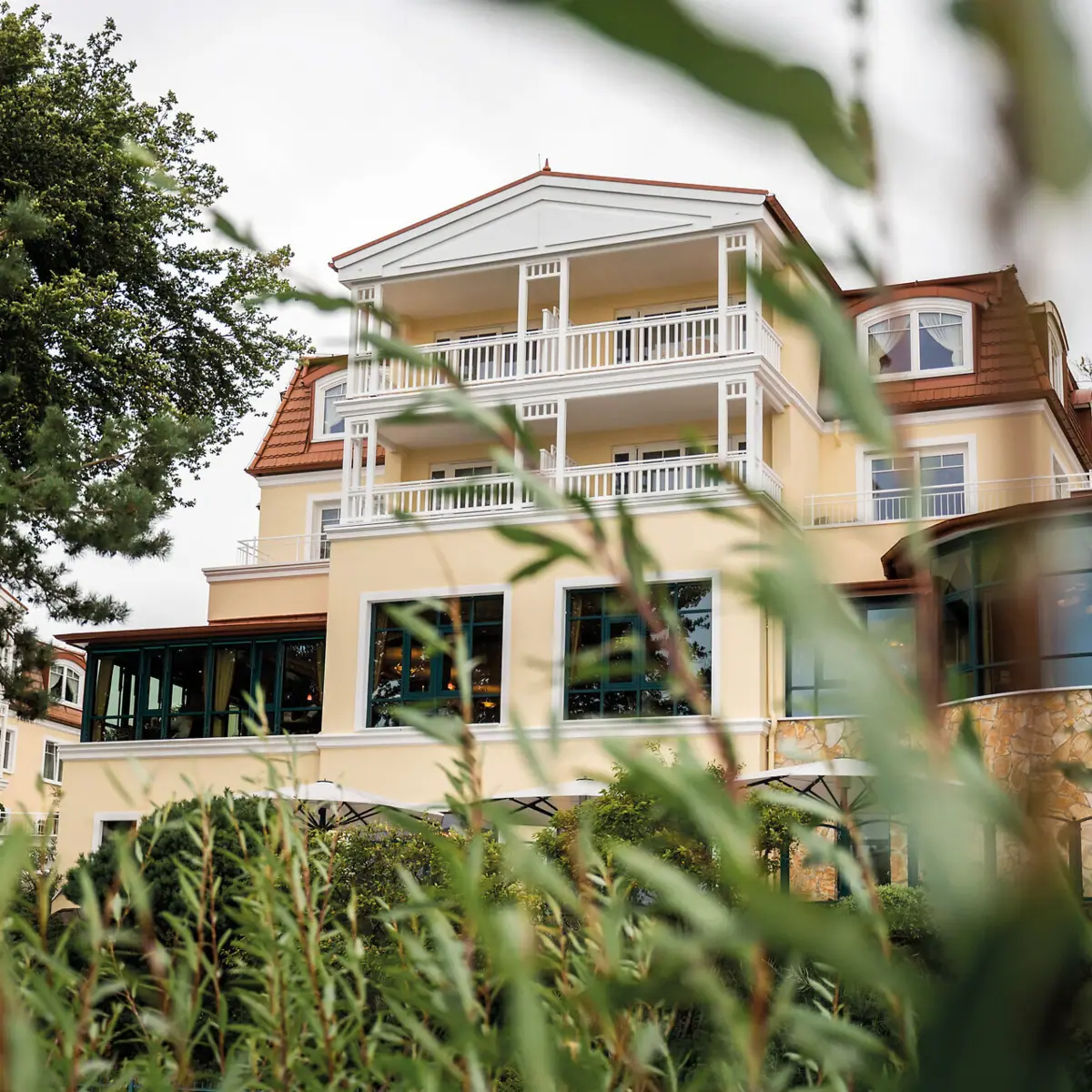 aja Hotel Usedom Ein Gebäude mit Fenstern und Bäumen im Hintergrund.