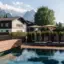 Außenpool aja Garmisch-Partenkirchen Ein Pool mit Stühlen und Sonnenschirmen neben einem Haus