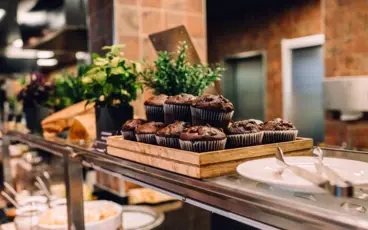 Auf einem Glasregal eines Buffets steht ein Tablett mit Schokoladenmuffins.