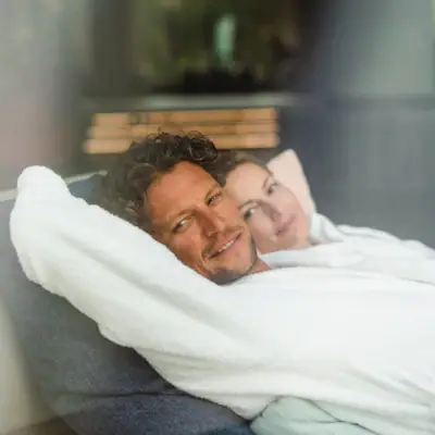 Inklusivleistungen im aja Warnemünde Ein Mann und eine Frau liegen bequem auf einem Sofa.