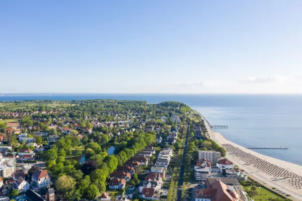Küste Travemünde Luftaufnahme einer Stadt am Wasser mit Gebäuden und Bäumen im Vordergrund.