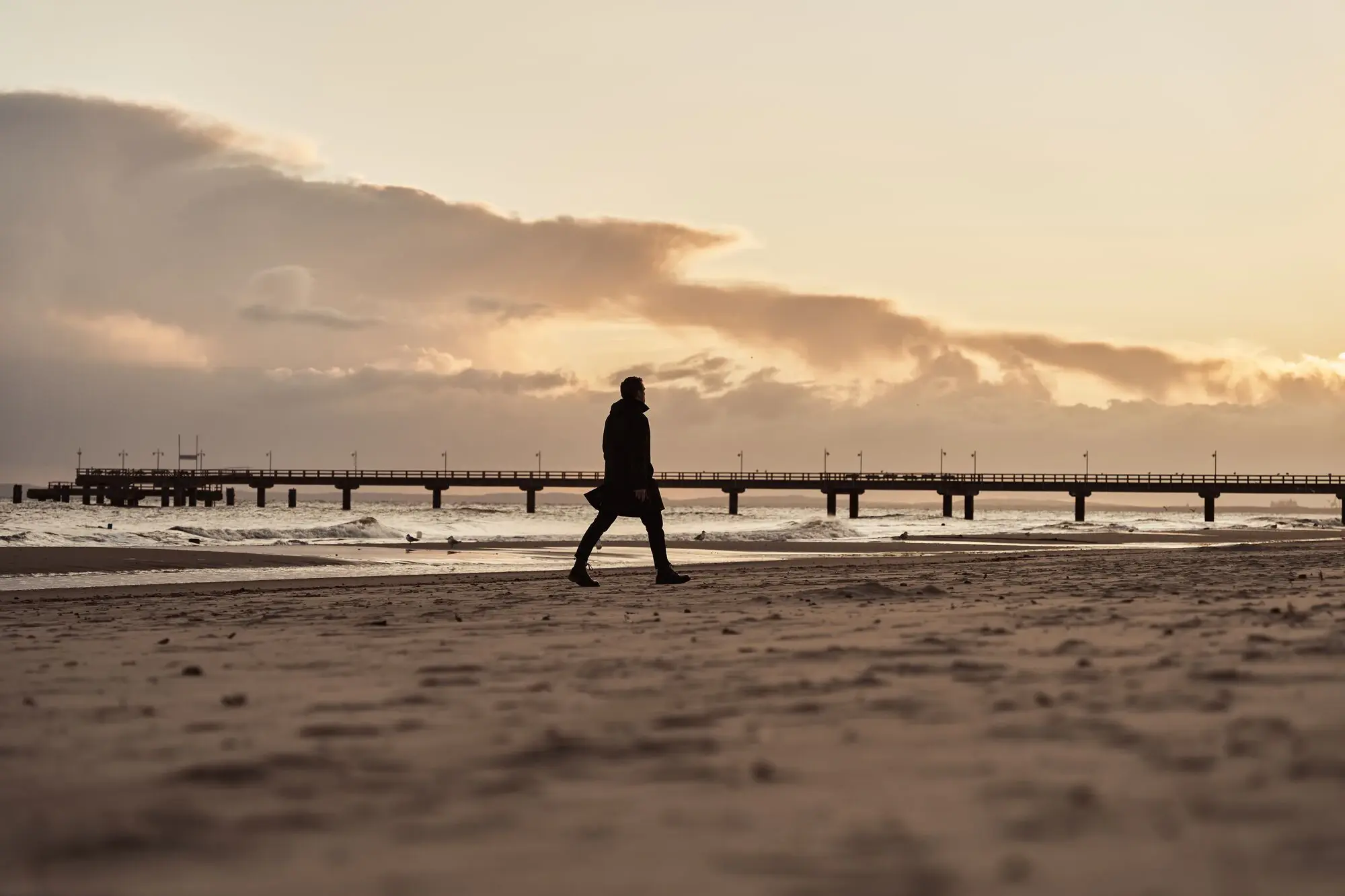 Strandspaziergang Bansin Eine Person, die am Strand bei Sonnenuntergang spaziert.