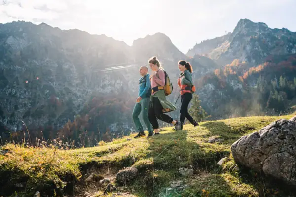 Wandern im Chiemgau Eine Gruppe von Menschen beim Wandern auf einem Hügel mit Bergen im Hintergrund.