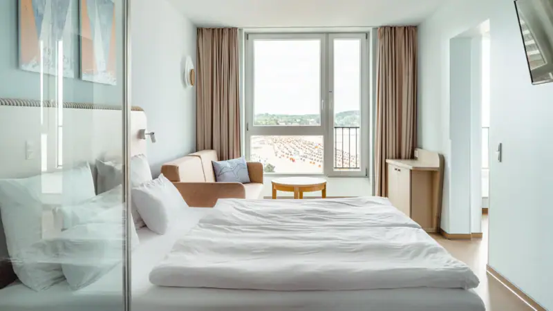 Zimmer im aja Travemünde Ein Zimmer mit einem Bett, einem Stuhl und einem Tisch.