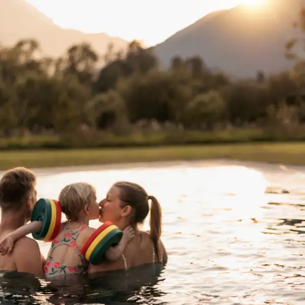 Familie im Pool Eine Gruppe von Menschen im Pool, ein Kind gibt einen Kuss.