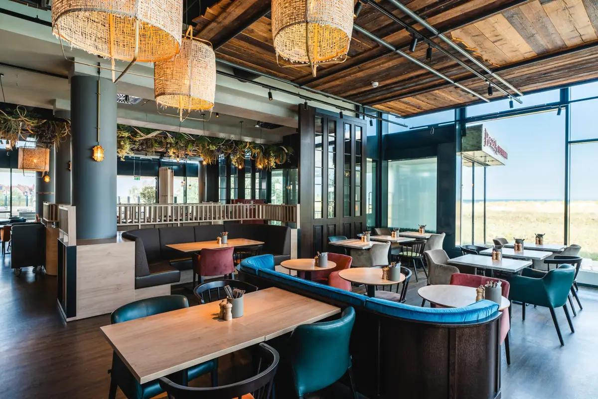 Restaurant im aja Warnemünde Ein Restaurant mit Tischen und Stühlen, maritim eingerichtet und dekoriert.
