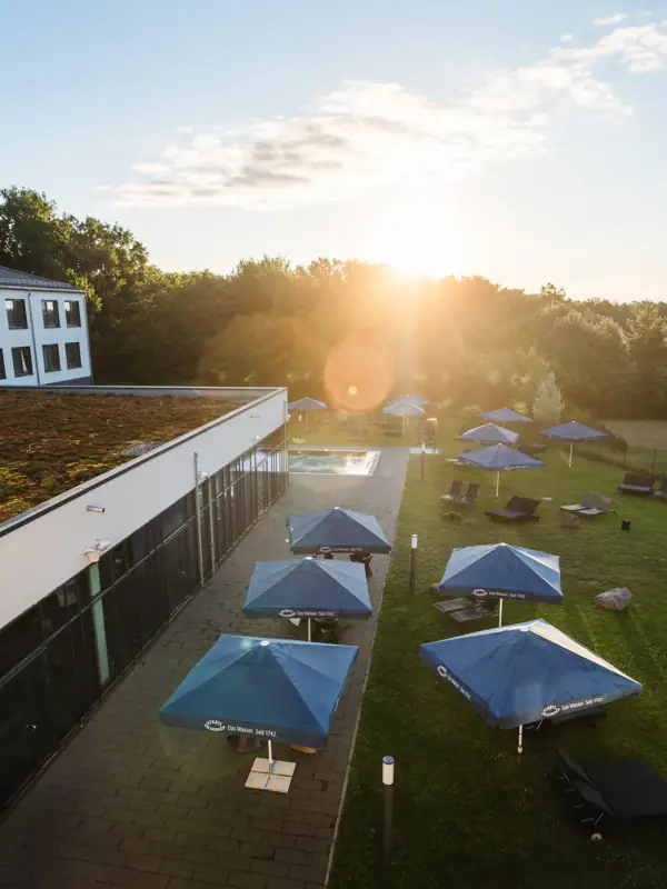 aja Bad Saarow Ein Gebäude mit Sonnenschirmen und Stühlen auf einer Rasenfläche.