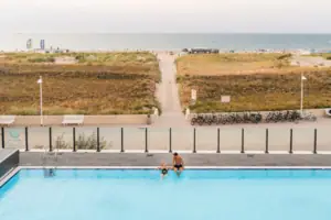 Außenpool Ein Mann und eine Frau am Rand eines Außenpools mit Blick auf den Strand und die Ostsee.